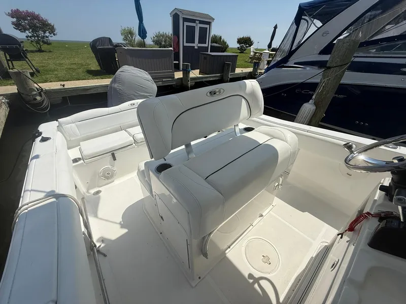 Slide: The Image of 2017 Sea Hunt Ultra 234 boat interior with white seating at dock. - 12