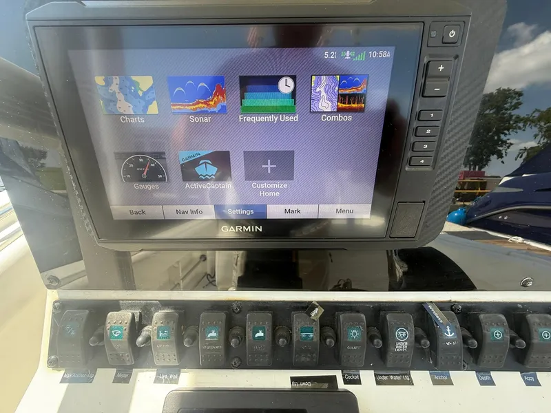 Slide: The Image of Garmin navigation display on 2017 Sea Hunt Ultra 234 boat dashboard with various control switches. - 14