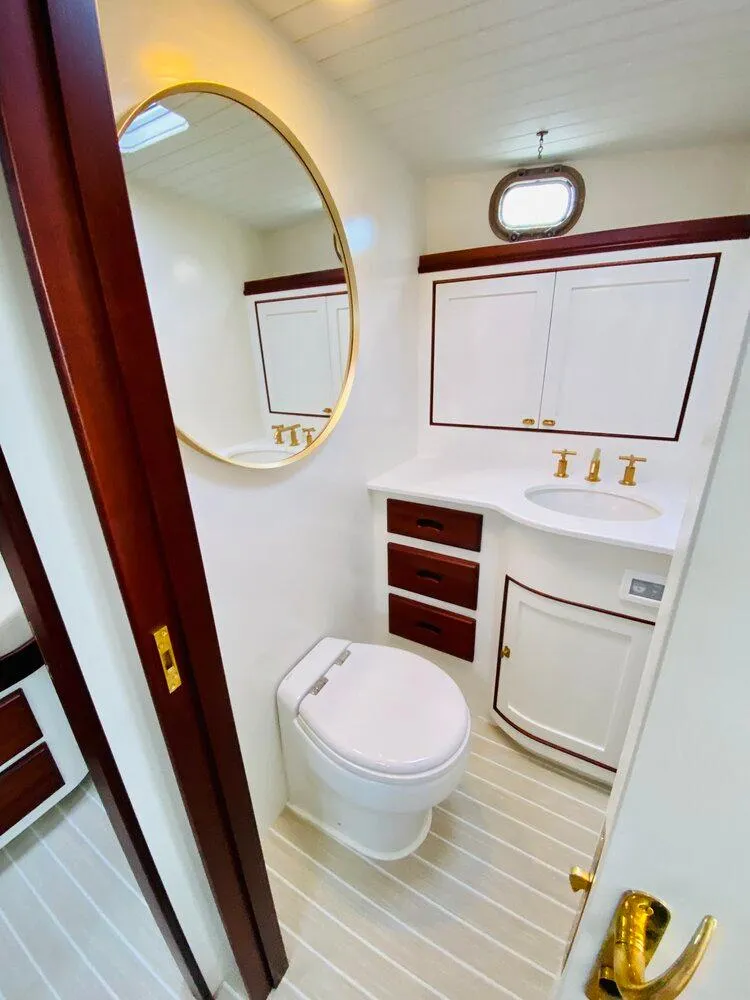 Slide: The Image of Elegant 2021 Mussel Ridge downeast boat bathroom with gold fixtures and round mirror. - 14