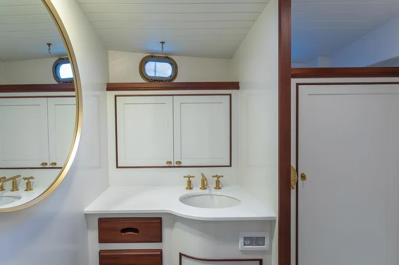 Slide: The Image of Elegant 2021 Mussel Ridge downeast boat bathroom with brass fixtures and round mirror. - 18