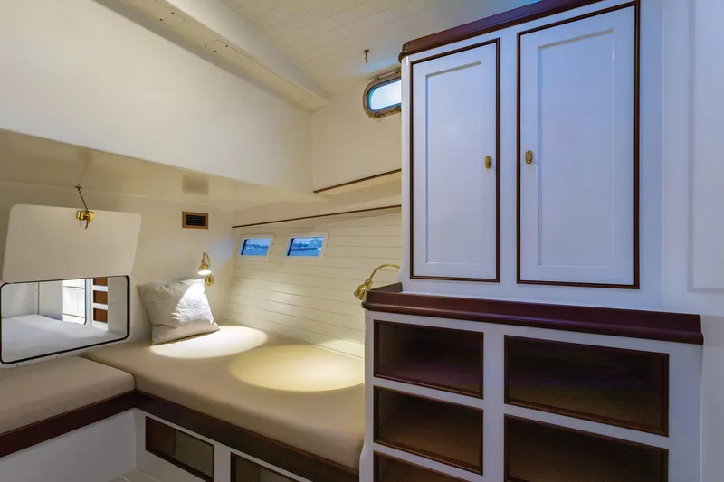 Slide: The Image of 2021 Mussel Ridge Downeast boat cabin interior with bed, storage, and portholes. - 19