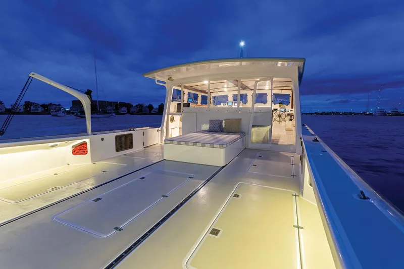 Slide: The Image of 2021 Mussel Ridge Downeast boat deck illuminated at dusk, showcasing spacious seating and modern design. - 21