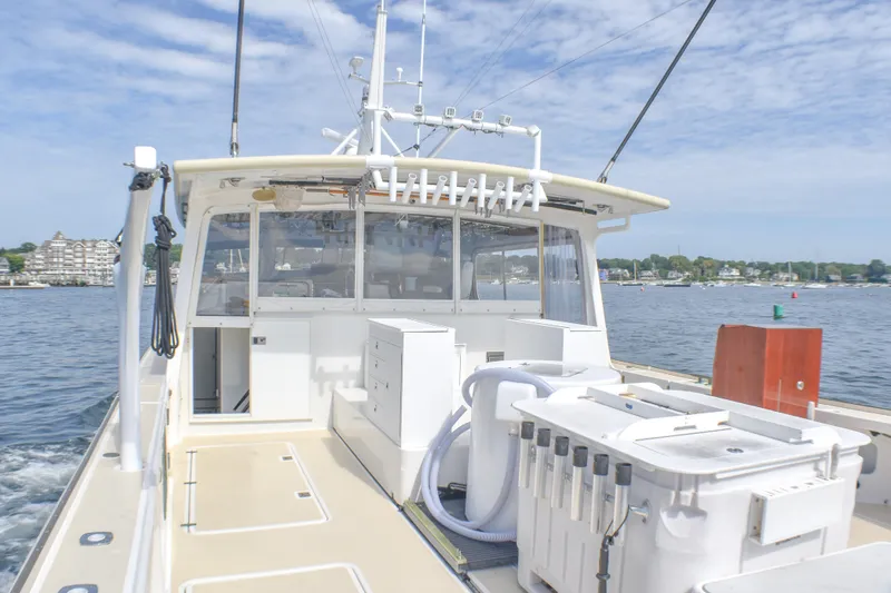 Slide: The Image of 2021 Mussel Ridge Downeast boat on water, featuring spacious deck and fishing equipment. - 26