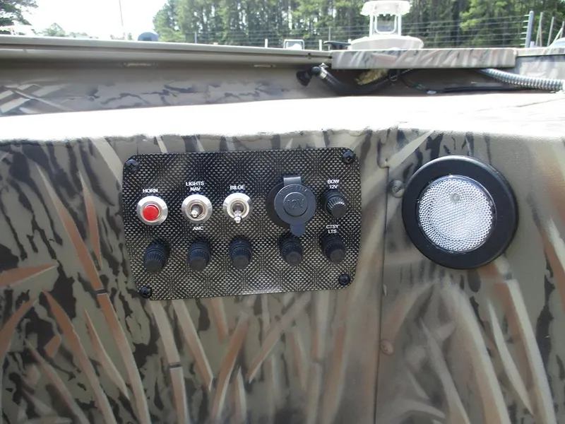Slide: The Image of Control panel of 2026 Tracker Grizzly 1654 T Sportsman boat with switches and camo design. - 22