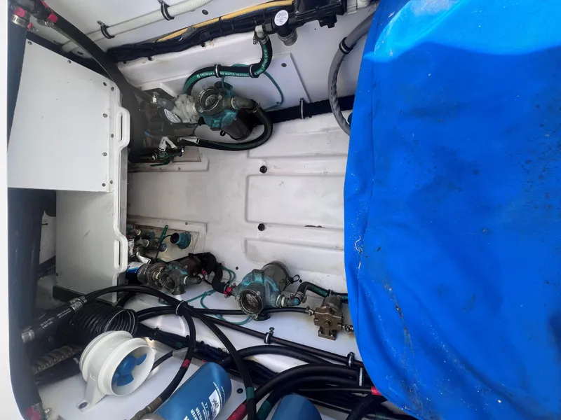 Slide: The Image of Engine compartment of a 2015 Pursuit OS 345 Offshore boat with visible machinery and blue cover. - 14
