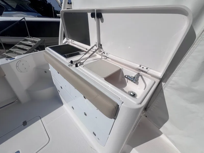 Slide: The Image of 2015 Pursuit OS 345 Offshore boat interior with sink and storage compartments. - 18