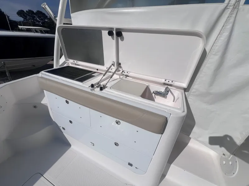 Slide: The Image of 2015 Pursuit OS 345 Offshore boat galley with sink and storage compartments. - 19