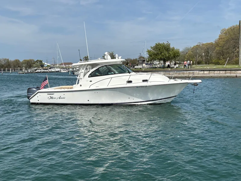 Slide: The Image of 2015 Pursuit OS 345 Offshore boat on water, American flag, clear sky, marina background. - 2