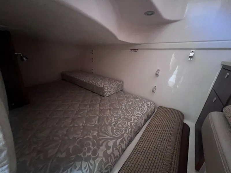 Slide: The Image of 2015 Pursuit OS 345 Offshore cabin interior with patterned bedding and compact design. - 33