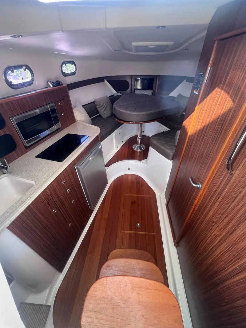 Slide: The Image of 2015 Pursuit OS 345 Offshore cabin interior with kitchen, seating, and wood finishes. - 37