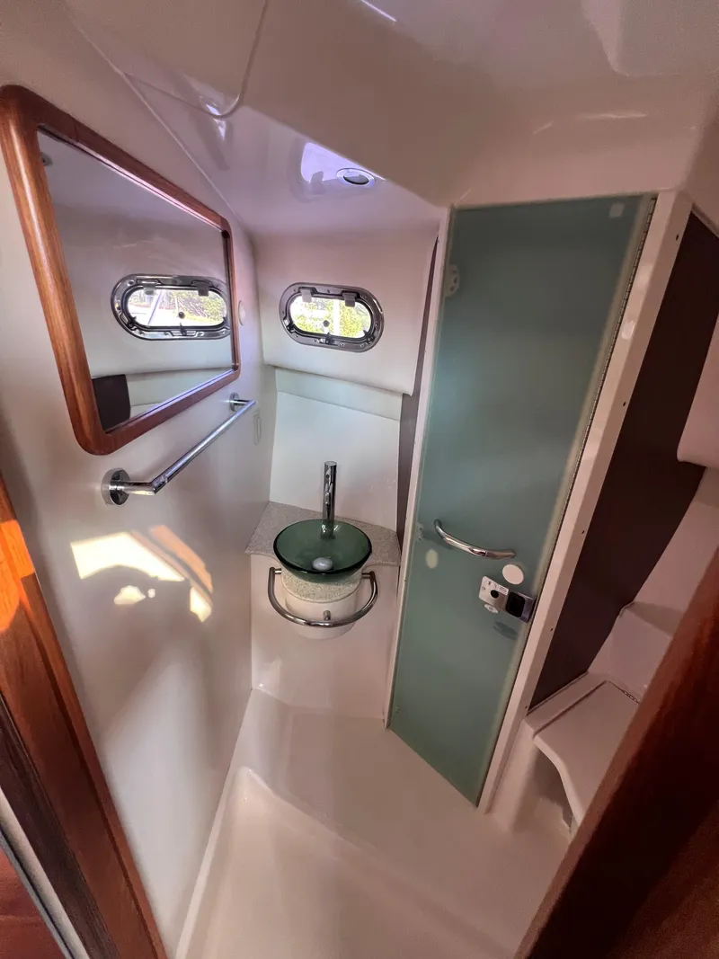 Slide: The Image of 2015 Pursuit OS 345 Offshore boat bathroom with modern sink and porthole windows. - 40