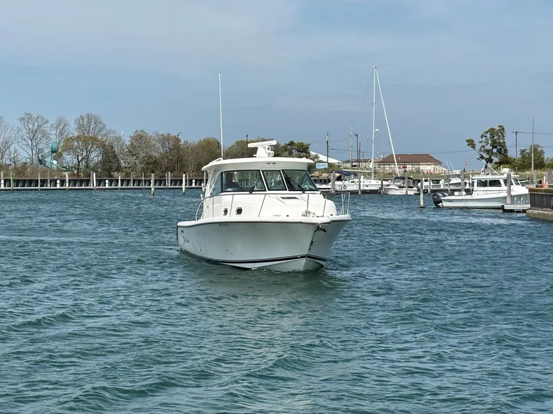 Slide: The Image of 2015 Pursuit OS 345 Offshore boat navigating a marina with clear skies. - 50