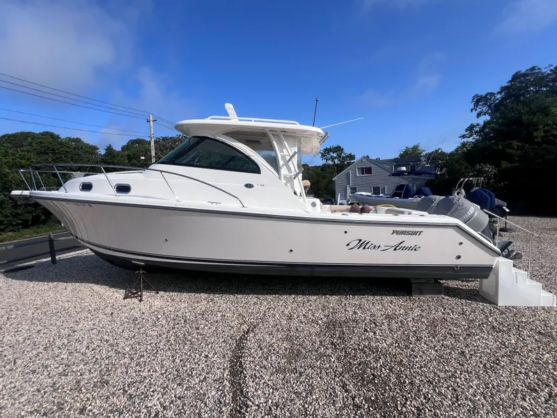 Slide: The Image of 2015 Pursuit OS 345 Offshore boat on gravel, named "Miss Annie," under clear blue sky. - 6