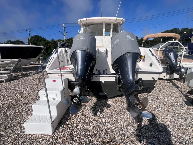 Slide: The Image of 2015 Pursuit OS 345 Offshore boat with twin Yamaha outboard engines on gravel lot. - 8