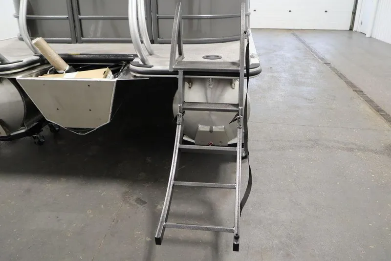 Slide: The Image of 2025 Bentley Pontoons 243 Navigator Tri-toon with rear boarding ladder in a garage setting. - 36