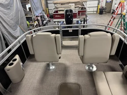 Slide: The Image of 2025 Sun Tracker Sportfish 24 XP3 interior with beige seating and cup holders in a garage. - 16