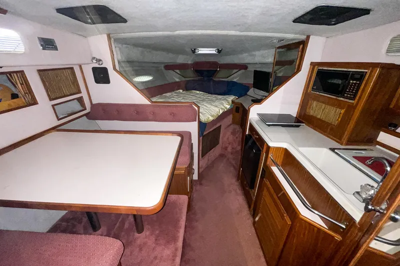 Slide: The Image of Interior of 1987 Sea Ray 300 Sundancer with dining area, kitchenette, and sleeping quarters. - 21