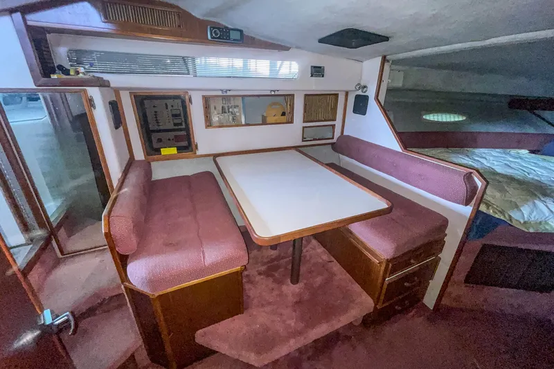 Slide: The Image of Interior of 1987 Sea Ray 300 Sundancer with dining area and maroon seating. - 22