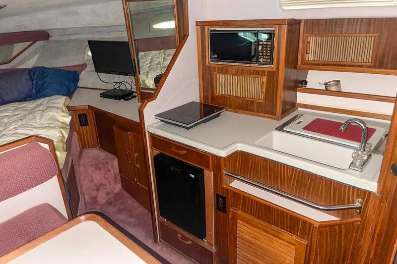 Slide: The Image of 1987 Sea Ray 300 Sundancer cabin interior with kitchenette, bed, and seating area. - 23