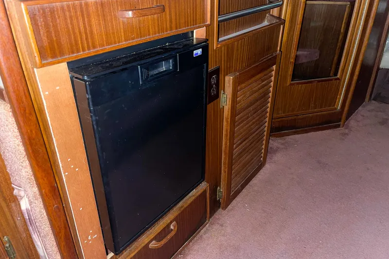 Slide: The Image of Interior of 1987 Sea Ray 300 Sundancer with wooden cabinetry and compact refrigerator. - 28