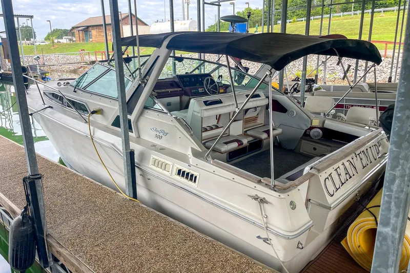 Slide: The Image of 1987 Sea Ray 300 Sundancer docked, featuring open cockpit and covered seating area. - 3
