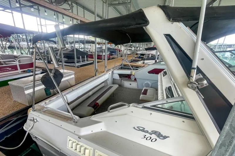 Slide: The Image of 1987 Sea Ray 300 Sundancer boat docked in a marina, featuring spacious seating and canopy. - 6