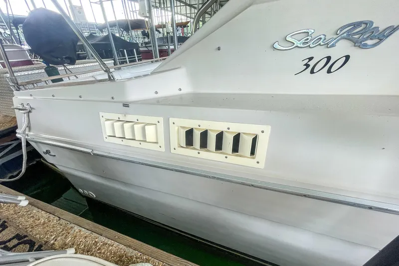 Slide: The Image of 1987 Sea Ray 300 Sundancer boat docked, showcasing side vents and model name. - 7