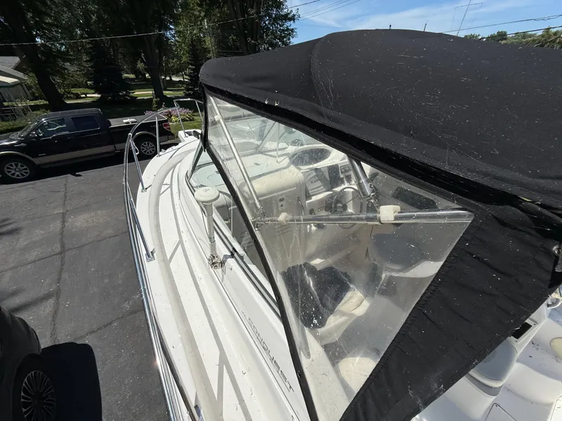 Slide: The Image of 2002 Boston Whaler 255 Conquest boat with black canopy, parked on driveway. - 25