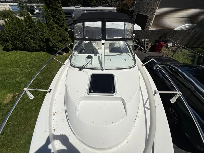 Slide: The Image of 2002 Boston Whaler 255 Conquest boat, top view, docked near greenery and vehicles. - 29