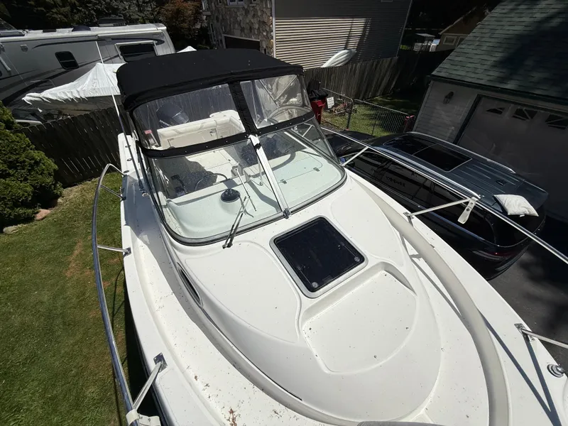 Slide: The Image of 2002 Boston Whaler 255 Conquest boat with black canopy, parked in a residential driveway. - 30