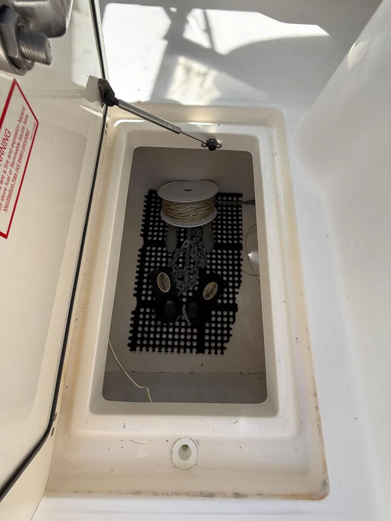 Slide: The Image of Storage compartment on a 2002 Boston Whaler 255 Conquest boat, featuring a rope spool. - 31