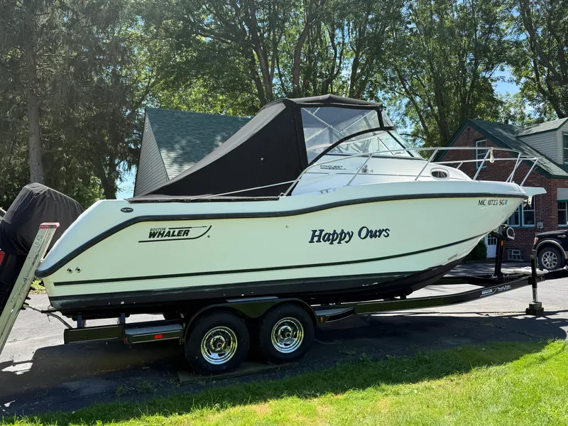 Slide: The Image of 2002 Boston Whaler 255 Conquest boat on trailer, named "Happy Ours," parked outdoors. - 40