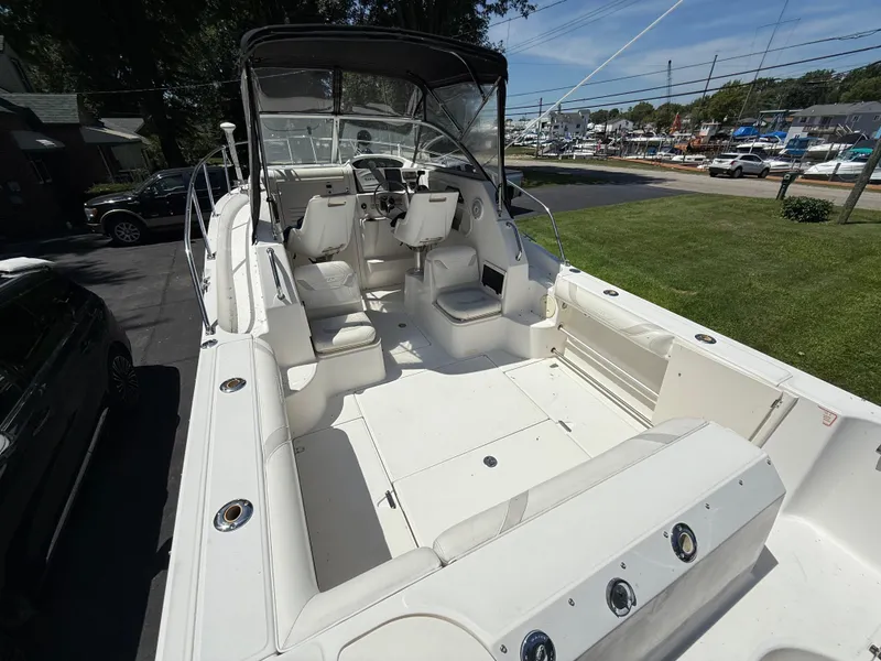 Slide: The Image of 2002 Boston Whaler 255 Conquest boat interior with seating and steering area, parked outdoors. - 9