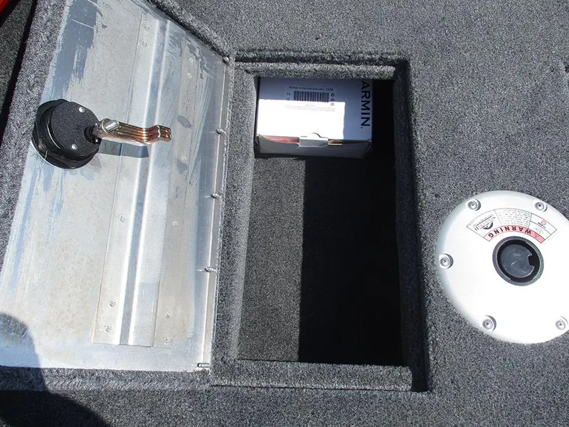 Slide: The Image of Storage compartment in 2026 Tracker Super Guide V-16 SC boat, featuring a Garmin box and warning label. - 20