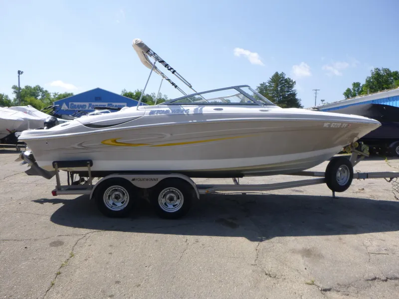 The Image of 2006 Four Winns 220 Horizon boat on trailer, parked outdoors under clear sky. - 1