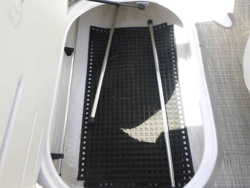 Slide: The Image of Storage compartment of a 2006 Four Winns 220 Horizon boat with black mat and metal poles. - 12