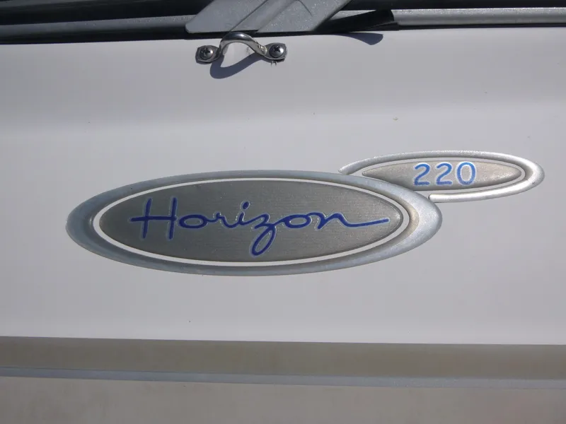Slide: The Image of 2006 Four Winns 220 Horizon boat emblem with blue lettering on a silver background. - 15