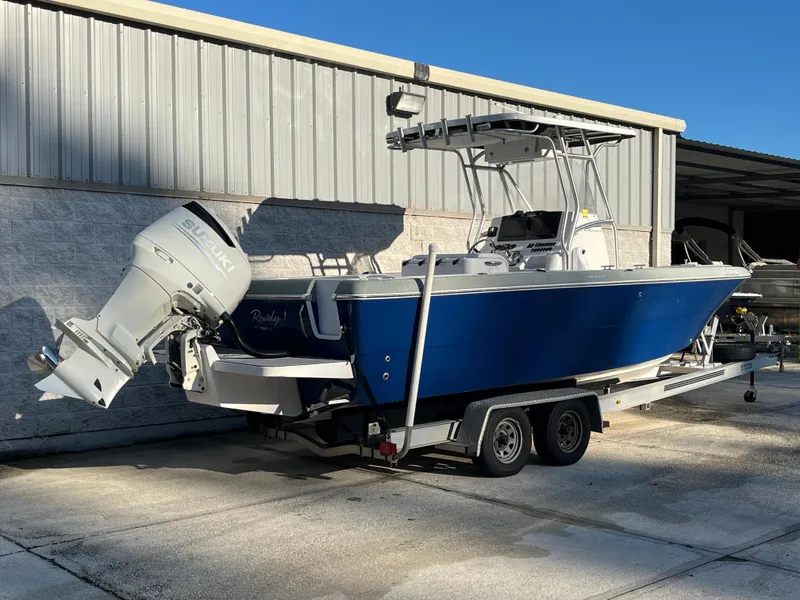 Slide: The Image of 2003 Pro-Line 25 Sport CC boat with Suzuki outboard motor on trailer, parked outdoors. - 2