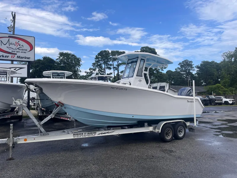 Slide: The Image of 2023 Tidewater 232 CC Adventure boat on trailer at dealership, under blue sky. - 1