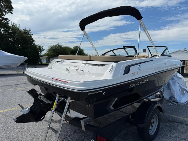 Slide: The Image of 2025 Bayliner VR4 Bowrider I/O boat on trailer, parked outdoors under a partly cloudy sky. - 3