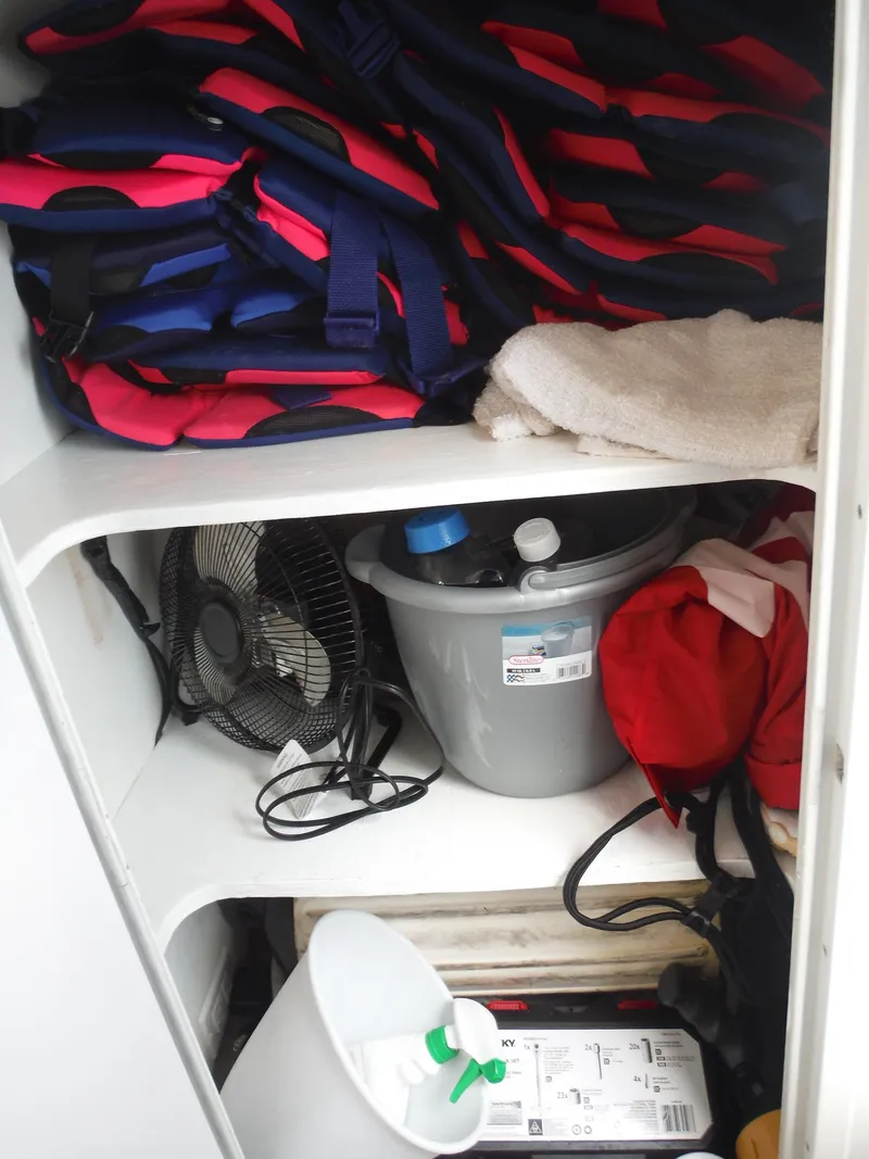 Slide: The Image of Storage compartment in 2003 Baja 36 Outlaw boat with life jackets, fan, and cleaning supplies. - 25