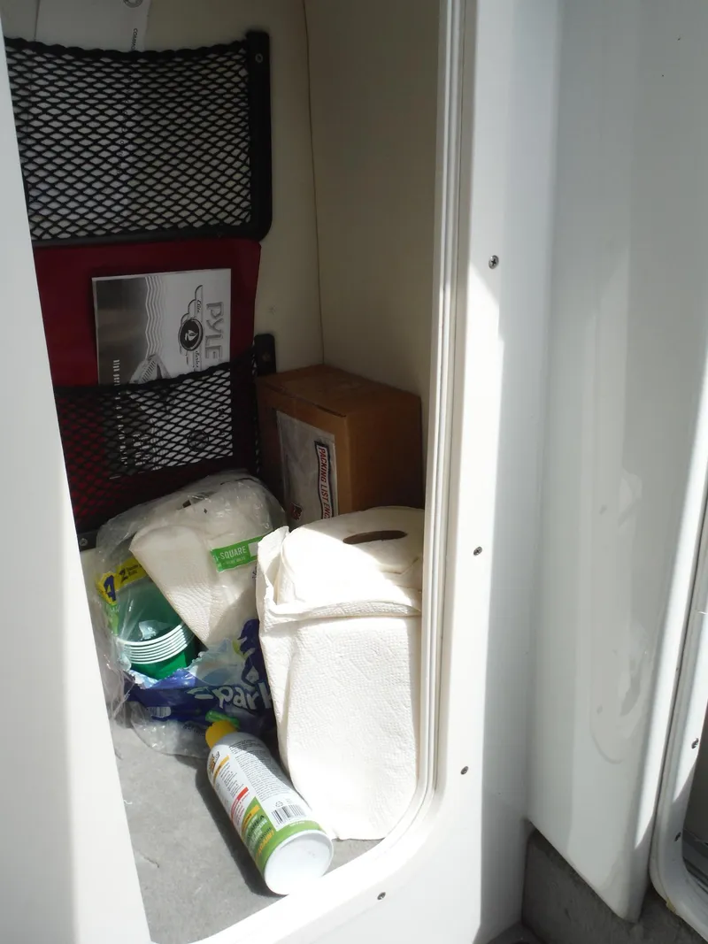 Slide: The Image of Storage compartment in a 2003 Baja 36 Outlaw boat with cleaning supplies and paper towels. - 26