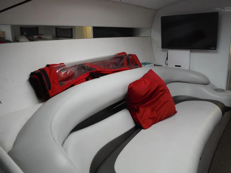 Slide: The Image of Interior of 2003 Baja 36 Outlaw boat with white seating, red pillow, and wall-mounted TV. - 30