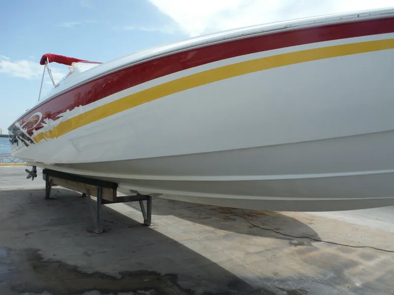 Slide: The Image of 2003 Baja 36 Outlaw boat with red and yellow stripes on a dock. - 44
