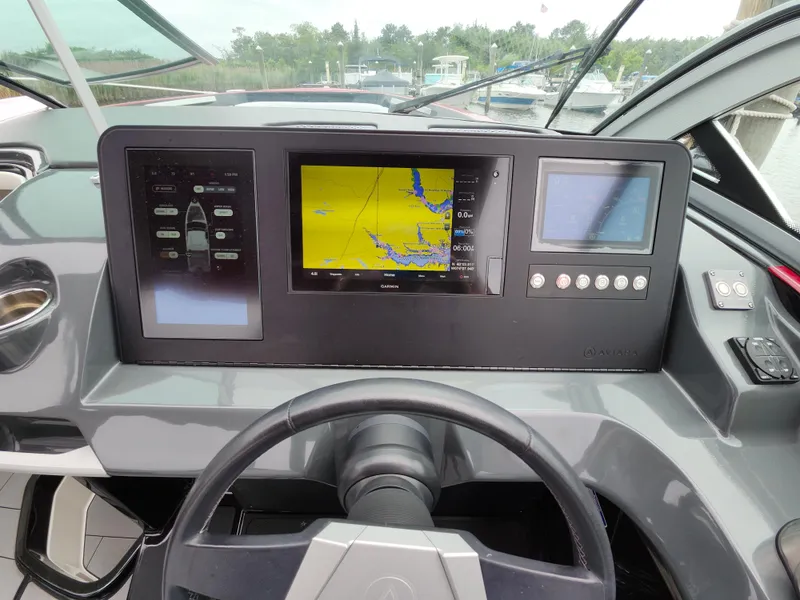 Slide: The Image of 2020 Aviara AV32 I/O dashboard with navigation screens and controls in a marina setting. - 10