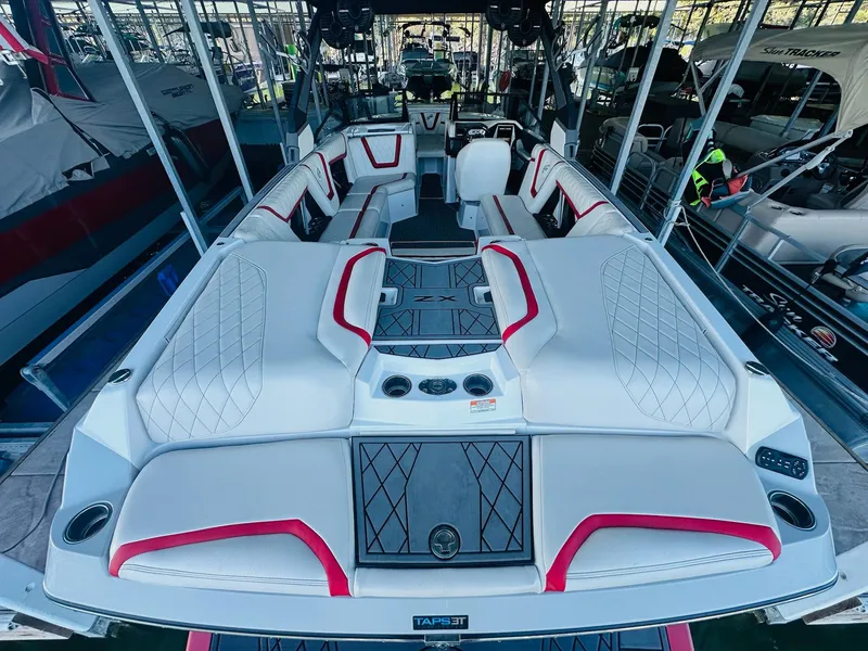 Slide: The Image of 2020 Tigé 25ZX boat interior with white and red seating, docked in a marina. - 14