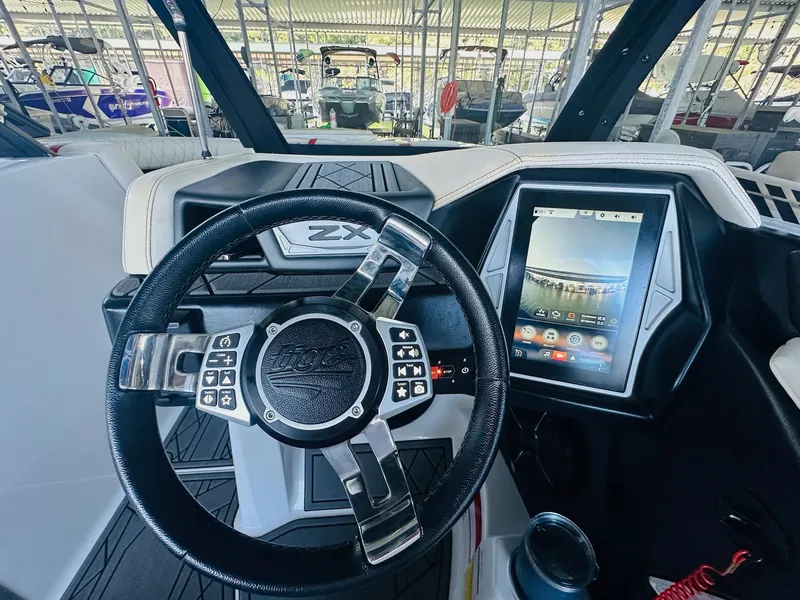 Slide: The Image of 2020 Tigé 25ZX boat dashboard with touchscreen and steering wheel in marina setting. - 18