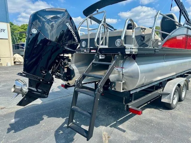 Slide: The Image of 2026 Barletta C24UC pontoon boat with Mercury outboard engine and trailer, parked outdoors. - 2