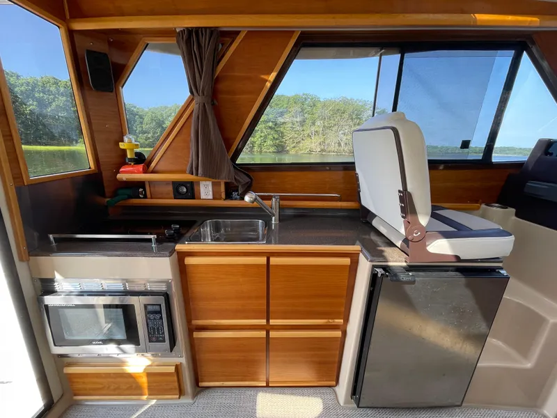Slide: The Image of 2017 Cutwater C-28 boat interior with kitchenette, featuring sink, microwave, and seating. - 10
