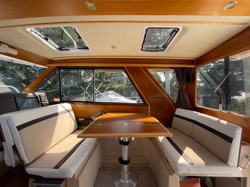 Slide: The Image of Interior of 2017 Cutwater C-28 boat with seating and table, featuring wood accents and windows. - 11